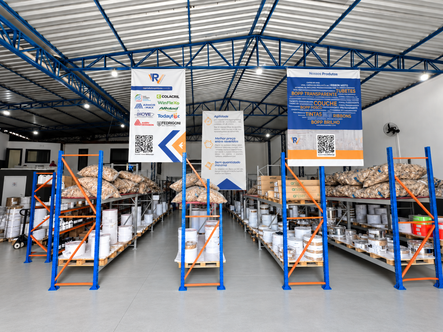Estoque organizado da RV Produtos Gráficos com prateleiras de bobinas e banners institucionais